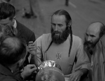 Bishop Asaiah talks with police and reporters outside the ruins of the headquarters of the Fountain of the World cult following an bomb attack by two former members, 11 December 1958. The Regents of the University of California (CC BY 4.0