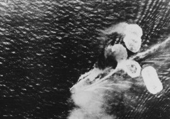 A photograph from a Japanese plane showing damage to HMS Repulse (bottom left) and HMS Prince of Wales (top right), 10 December 1941. US Naval History and Heritage Command. Public Domain.